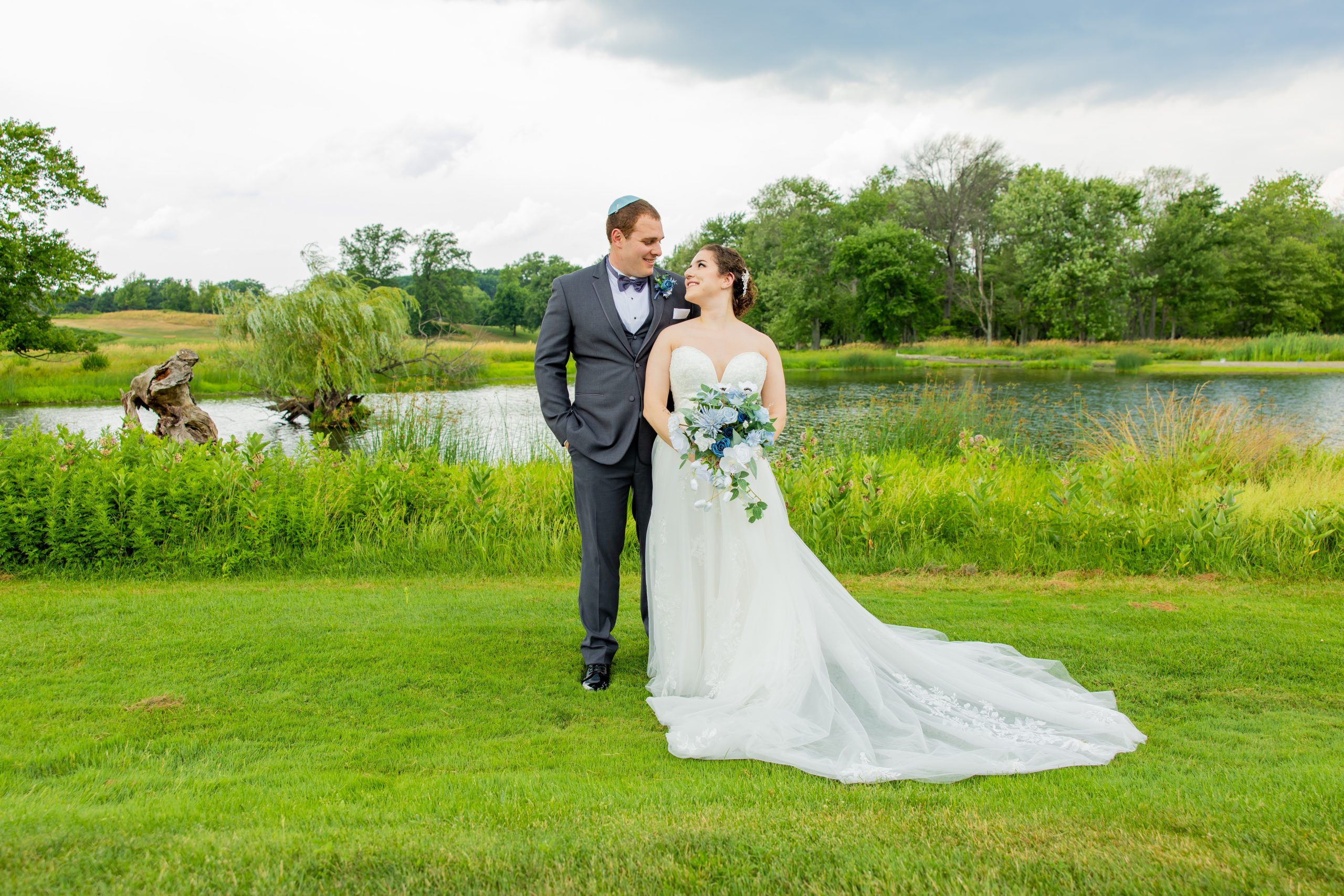 A bride and groom outdoors in front of a body of water at The Clubhouse at Galloping Hill in Kenilworth, New Jersey