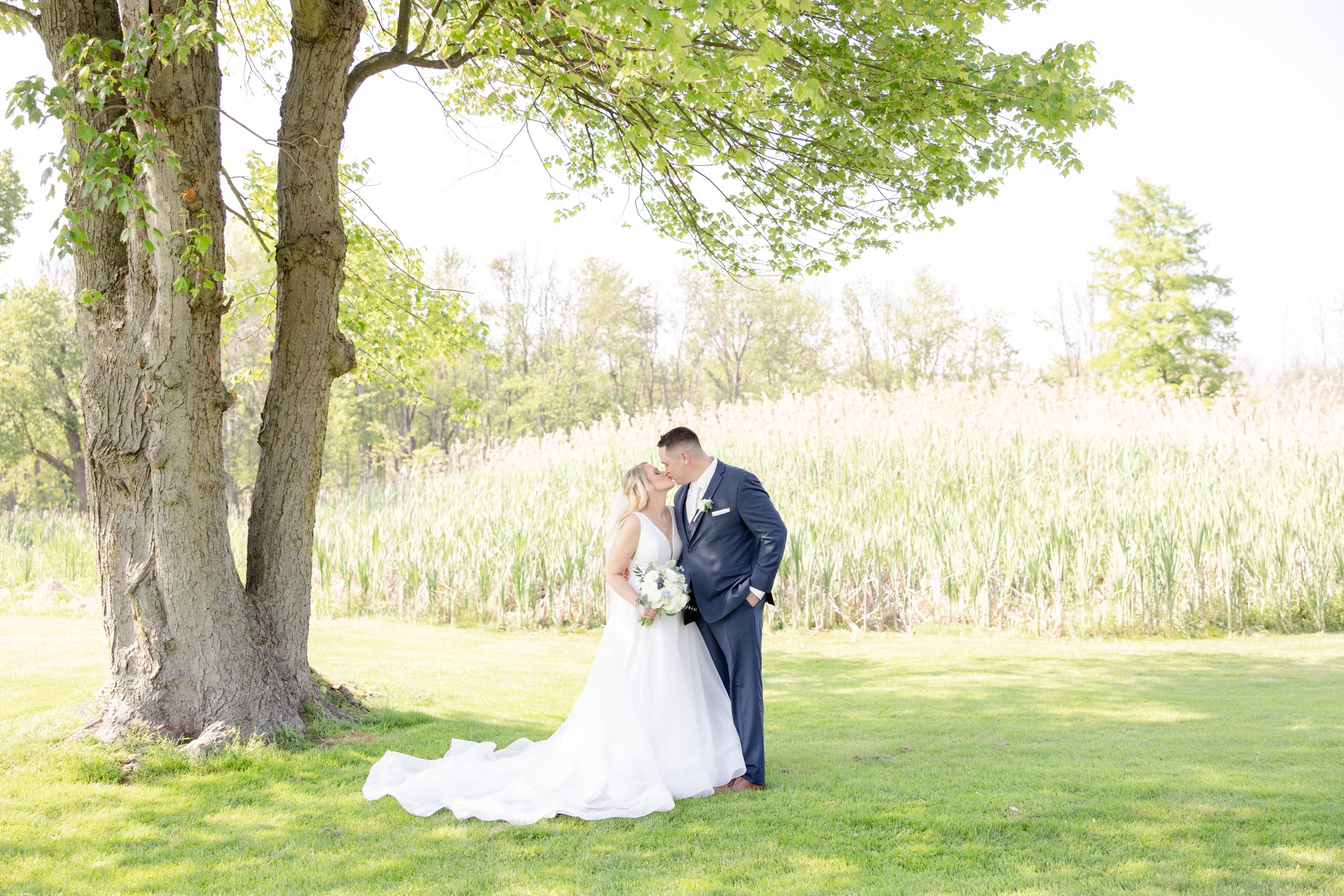 Bride and groom share a kiss under a tree on the golf course at The Clubhouse at Galloping Hill in Kenilworth, New Jersey
