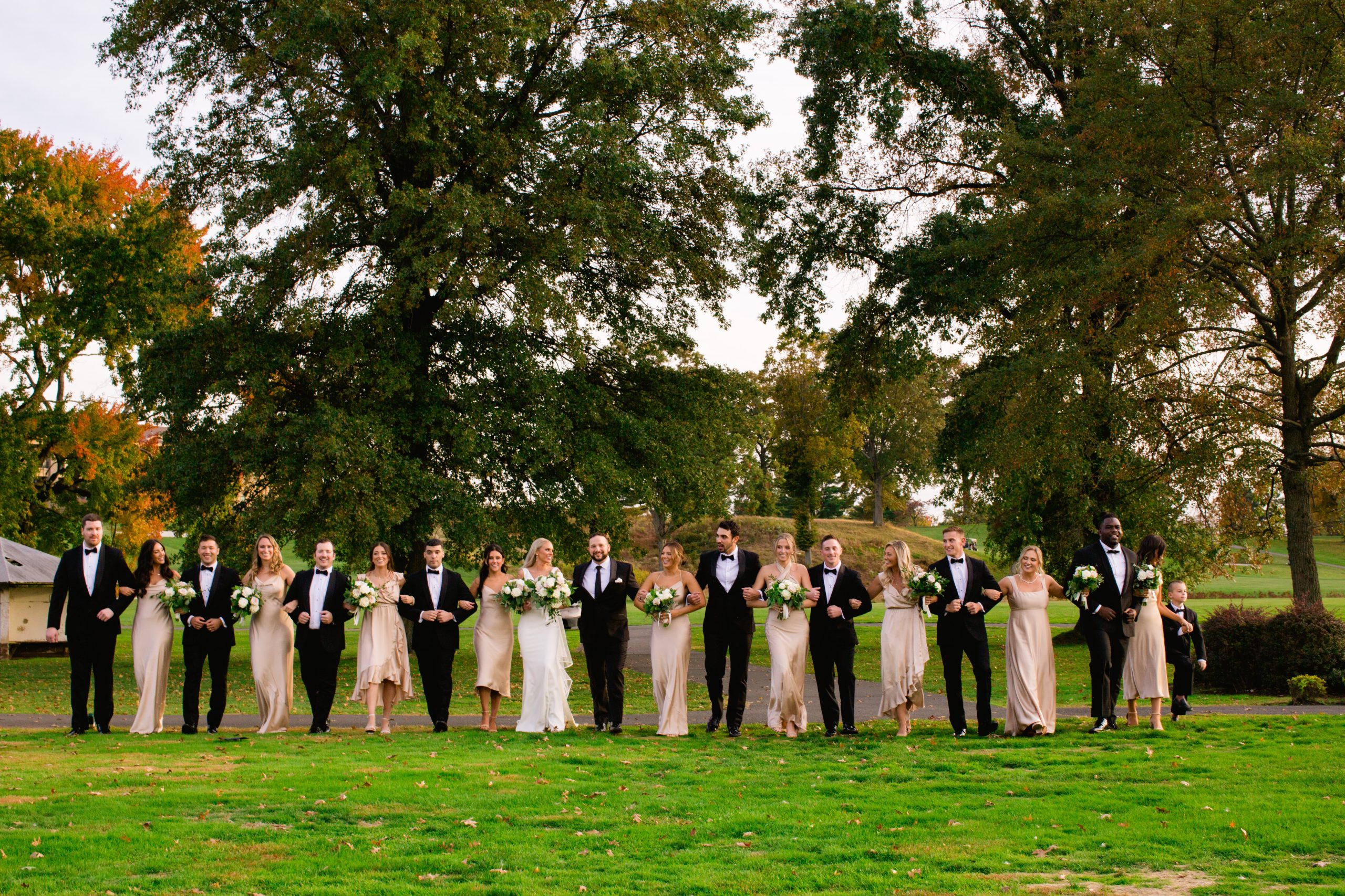 A bride and groom with their wedding party walking on the golf course at The Clubhouse at Galloping Hill in Kenilworth, New Jersey