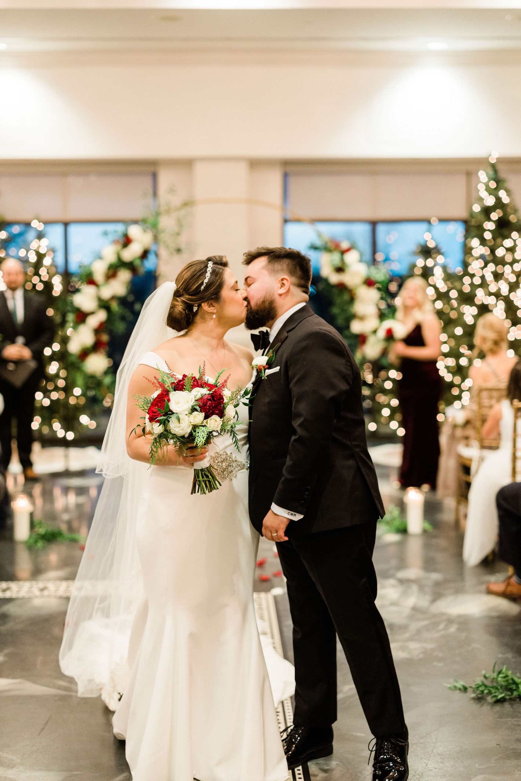A bride and groom share a kiss in front of their ornate display of greenery and lights at The Clubhouse at Galloping Hill in Kenilworth, New Jersey